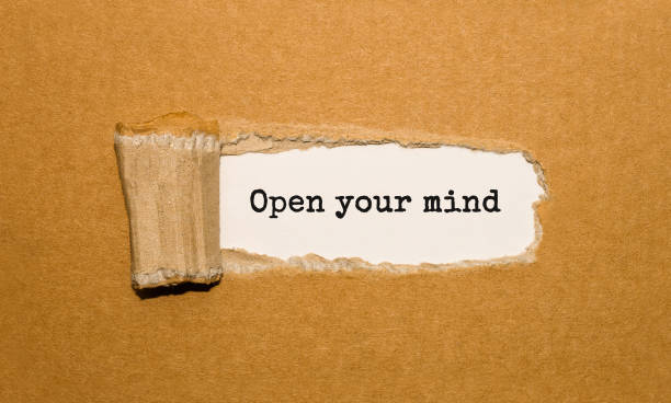 De tekst 'Open your mind' verschijnt achter gescheurd bruin papier, als symbool voor groei, inzicht en persoonlijke ontwikkeling bij volwassenen.