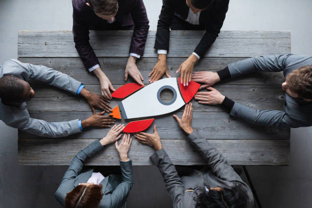 Conceptbeeld van een zakelijk team dat samen een raket lanceert als symbool voor succes, samenwerking en leiderschap met draagvlak.