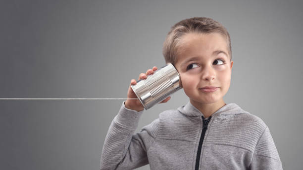 Jongen met een blikken telefoon die luistert naar goed nieuws, als symbool voor communicatie, geld en keuzes maken.